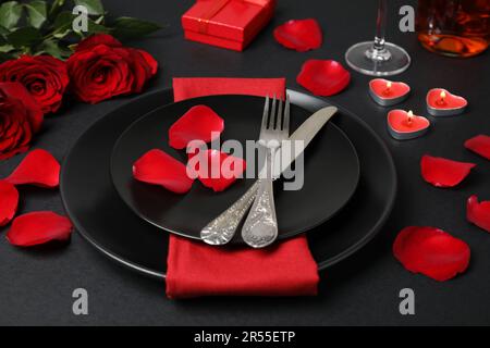 Bella tavola impostazione con candele brucianti e bouquet sul tavolo nero per cena romantica Foto Stock