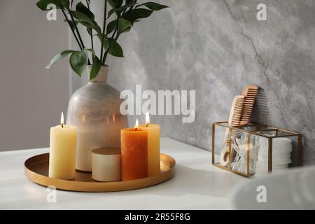 Bella pianta in vaso e candele che bruciano sulla vanità della stanza da bagno Foto Stock