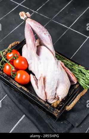 Selvaggina uccello guineafowl crudo, faraona pronto per la cottura. Sfondo nero. Vista dall'alto. Foto Stock