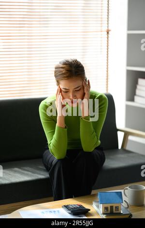 Stressata donna millenaria seduta sul divano di gestione delle finanze familiari frustrati da problemi finanziari familiari Foto Stock