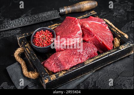 Venison crudo crudo crudo Carne cara, carne di selvaggina. Sfondo nero. Vista dall'alto. Foto Stock