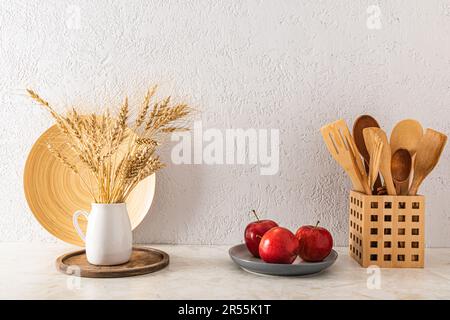 Vista frontale del piano cucina con mele rosse sul piatto e prodotti da cucina ecologici. Parete grigia con texture Foto Stock