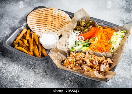 Doner kebab Shawarma su un piatto con patatine fritte e insalata in scatola per andare, da asporto. Sfondo bianco. Vista dall'alto. Foto Stock