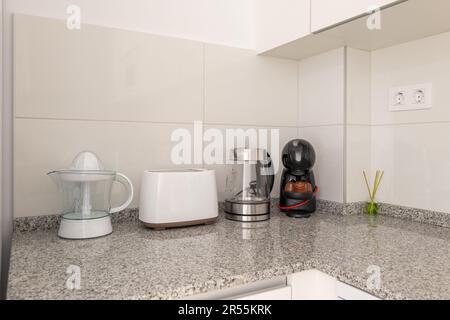 Primo piano di un tavolo da cucina con una centrifuga e elettrodomestici da cucina con piastrelle bianche e armadi da cucina. Il concetto di utensili domestici e. Foto Stock