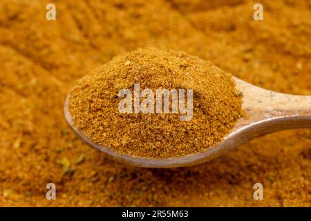 Cumulo di polvere di cajun come sfondo, spezia o condimento come sfondo. Primo piano della polvere di cajun in un cucchiaio di legno Foto Stock