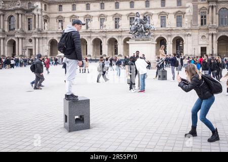 I turisti scattano foto di fronte alla piramide Lovre nel cortile dell'elegante Palais Royale in attesa di entrare nel museo d'arte del Louvre in una tranquilla giornata grigia di primavera a Parigi, in Francia. In mezzo a una folla di visitatori e turisti, questi capolavori architettonici mescolano modernità e storia, invitando esplorazione e apprezzamento. Osserva l'armoniosa miscela di vecchio e nuovo, mentre il ricco patrimonio culturale della città prende vita in mezzo alla vibrante energia di una popolare destinazione di viaggio. Foto Stock