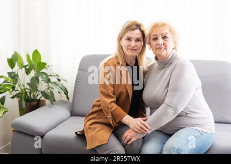 Primo piano immagine madre anziana figlia adulta seduta sul divano interno sorridente cercando in posa per la fotocamera abbracciare si sente felice passare il tempo insieme, concetto Foto Stock