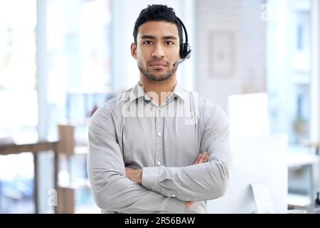 Call center, uomo e ritratto con braccia incrociate in ufficio, telemarketing o faccia seria per il lavoro crm. Giovane consulente indiano, cuffie voip e. Foto Stock