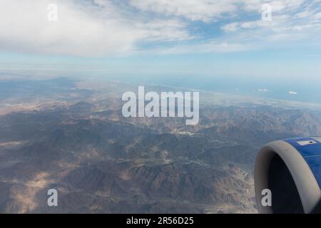 Vista aerea della finestra Aeroplane del paesaggio con le nuvole che proiettano ombre scure sul terreno montuoso. Foto Stock