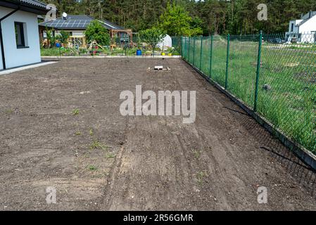 Livellare il chernozem nel cortile con un pallet pesato con un cubo di cemento, preparandosi alla semina del prato. Foto Stock