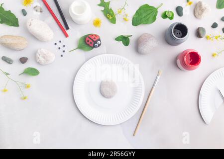 Disegnare una coccinella su una pietra con vernici acriliche. Gli hobby domestici sono autentici. Opere d'arte su pietre. Foto Stock