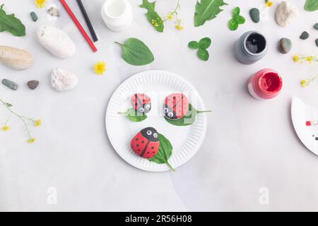 Disegnare una coccinella su una pietra con vernici acriliche. Gli hobby domestici sono autentici. Opere d'arte su pietre. Foto Stock