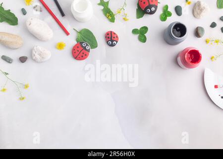 Disegnare una coccinella su una pietra con vernici acriliche. Gli hobby domestici sono autentici. Opere d'arte su pietre. Foto Stock