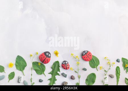 Disegnare una coccinella su una pietra con vernici acriliche. Gli hobby domestici sono autentici. Opere d'arte su pietre. Foto Stock