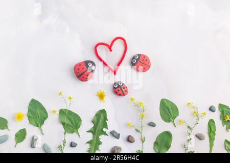 Disegnare una coccinella su una pietra con vernici acriliche. Gli hobby domestici sono autentici. Opere d'arte su pietre. Foto Stock