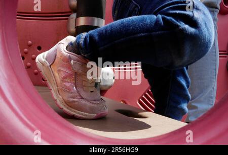 Piedi di una bambina di due anni che scende. Indossa con orgoglio le sneaker rosa alla moda Foto Stock