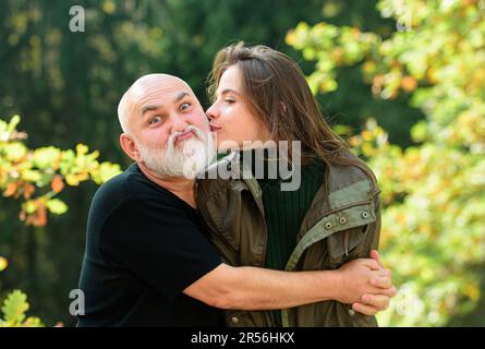 Ritratto o sorridente padre anziano e figlia cresciuta baciando, abbracciando, coccolandosi. Concetto di due generazioni. Autunnale a piedi. Foto Stock