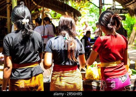 Giovani donne che preparano offerte di fiori agli dei in Taman Beji Griya Waterfall, Kabupaten Badung, Bali, Indonesia Foto Stock
