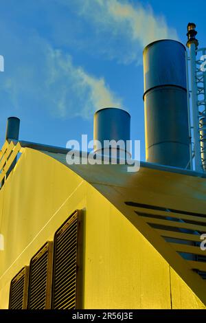 Primo piano degli imbuti di un traghetto per passeggeri che emette fumo contro un cielo blu chiaro. Foto Stock