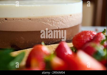 Dolce mousse dessert Triple cioccolato con fragole sfocate in primo piano. Pasticceria. Ancora la vita con il cibo Foto Stock