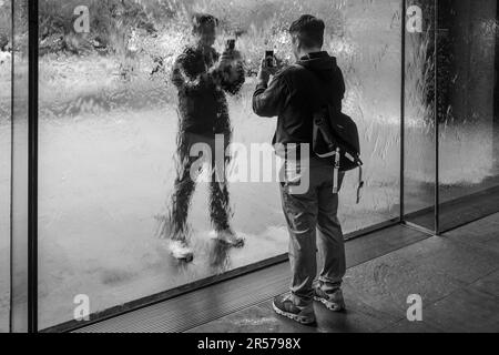 I visitatori si fotografano a vicenda attraverso il Waterwall presso la National Gallery of Victoria, Melbourne, Australia Foto Stock