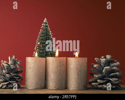Tre candele dell'Avvento che bruciano su sfondo rosso con decorazione di Natale Foto Stock