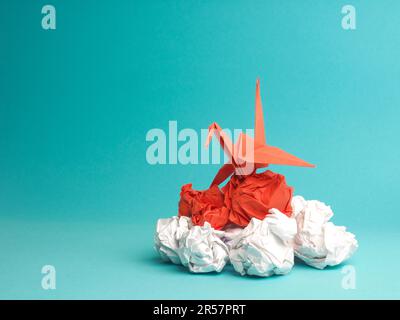 Nuove idee o concetto di trasformazione con palline di carta sminuzzate e una gru, lavoro di squadra, creatività, concetto aziendale Foto Stock