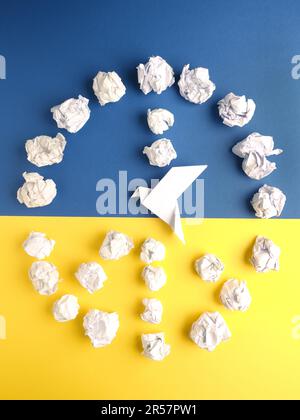 Simbolo di pace di palle di carta sbriciolate con una colomba di origami su carta blu e gialla come bandiera Ucraina Foto Stock