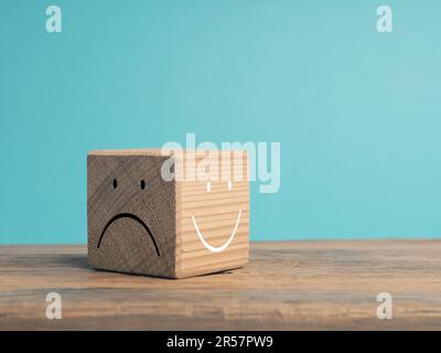 Un cubo di legno con lato chiaro e scuro, una volta con volto sorridente e con volto triste, c'è sempre la possibilità di scegliere, quale faccia scegliete? Foto Stock