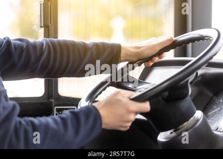 Primo piano delle mani del conducente sul volante durante la guida dell'autobus, concetto di trasporto pubblico Foto Stock