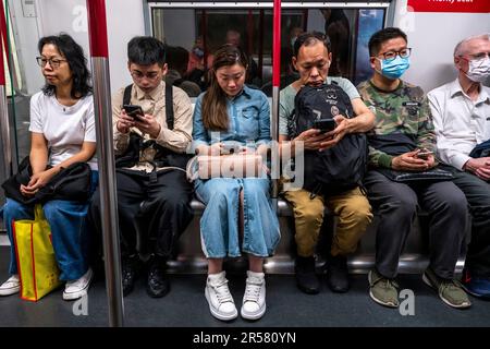 Persone che utilizzano il proprio smartphone su Un treno MTR, Hong Kong, Cina. Foto Stock