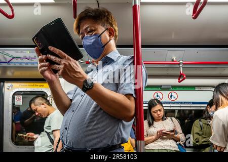 Persone che utilizzano il proprio smartphone su Un treno MTR, Hong Kong, Cina. Foto Stock