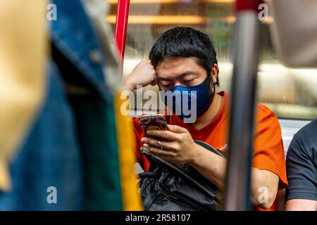 Persone che utilizzano il proprio smartphone su Un treno MTR, Hong Kong, Cina. Foto Stock