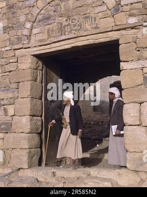 Due persone in abiti tradizionali presso le mura della città di Thula, Thulla, Yemen Foto Stock