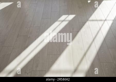 Parquet di legno grigio o pavimento laminato con luce dalle finestre in casa moderna Foto Stock