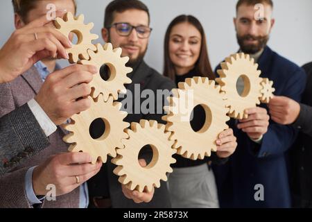 Primo piano di sette ingranaggi in legno, assemblati da amici e colleghi in un unico meccanismo. Foto Stock