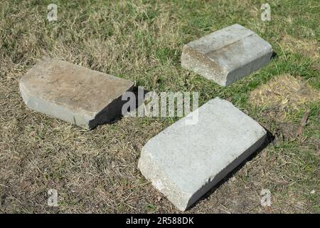 Blocchi di cemento giacciono sull'erba. Detriti di costruzione nel parco. Il blocco di cemento si trova a terra. Rifiuti industriali. Foto Stock