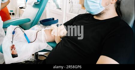 L'uomo di mezza età dona sangue in laboratorio medico. Il donatore di sangue dona sangue per salvare la vita e per la ricerca medica. Giornata internazionale della donazione di sangue. Foto Stock