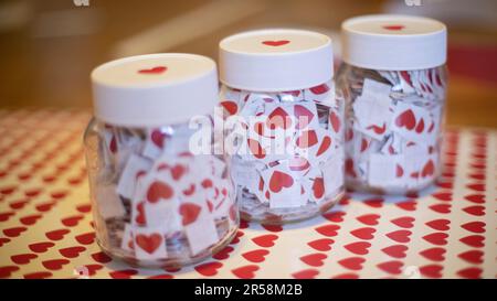 Cuori in vasi. Adesivi fatti a casa. Molti cuori rossi in vasetti di vetro. Tappi bianchi. Piccoli adesivi. Foto Stock