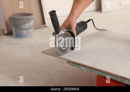 Lavoratore che utilizza la sega con lama circolare diamantata per il taglio di piastrelle all'interno, primo piano Foto Stock