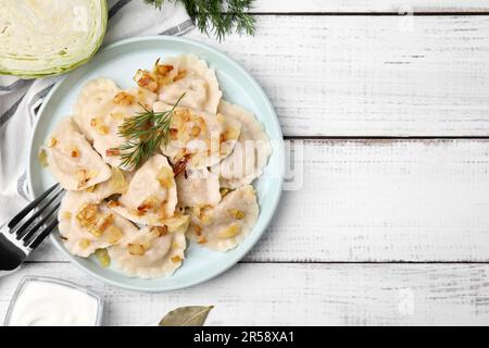 Gnocchi cotti (varenyky) con gustoso ripieno, cipolle fritte e aneto su tavola di legno, piatto. Spazio per il testo Foto Stock