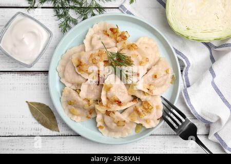 Gnocchi cotti (varenyky) con gustoso ripieno, cipolle fritte e aneto su tavola di legno, piatto Foto Stock