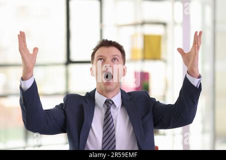 Un uomo d'affari eccitato urla e alza le mani in ufficio Foto Stock
