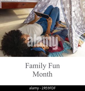 Testo del mese per il divertimento della famiglia e madre e figlia biraciale utilizzando un tablet digitale e sdraiati a casa Foto Stock