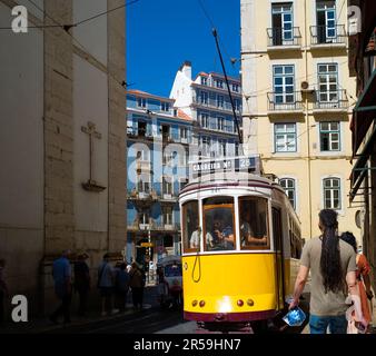 Nelle strette strade di Lisbona un famoso tram numero 28 passa molto vicino ai pedoni Foto Stock