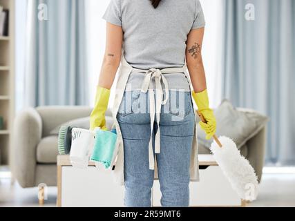 Donna, governante e schiena con forniture per la pulizia, l'igiene o la disinfezione nel soggiorno di casa. Vista posteriore della persona, del pulitore o della cameriera Foto Stock