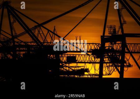 Dettagli di gigantesche gru a portale per container al tramonto Foto Stock