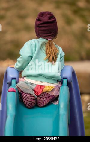 Ragazza giovane che guarda lontano seduta in cima a uno scivolo per bambini Foto Stock