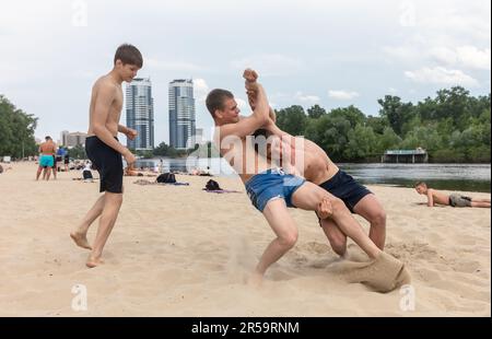 KIEV, UCRAINA - Maggio. 27, 2023: Gli adolescenti si rilassano e si divertono in spiaggia lottando sulla spiaggia della città di Kiev, nonostante i quotidiani attacchi missilistici contro la capitale Ucraina. Foto Stock