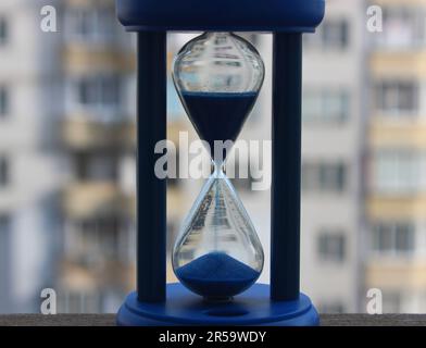 Vista ravvicinata della sabbia caduta all'interno della vetrata in vetro sabbiato sulla facciata sfocata del grattacielo sullo sfondo Foto Stock